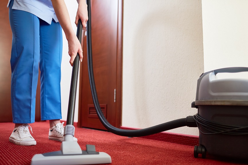 Hotel maid cleaning carpet with vacuum cleaner